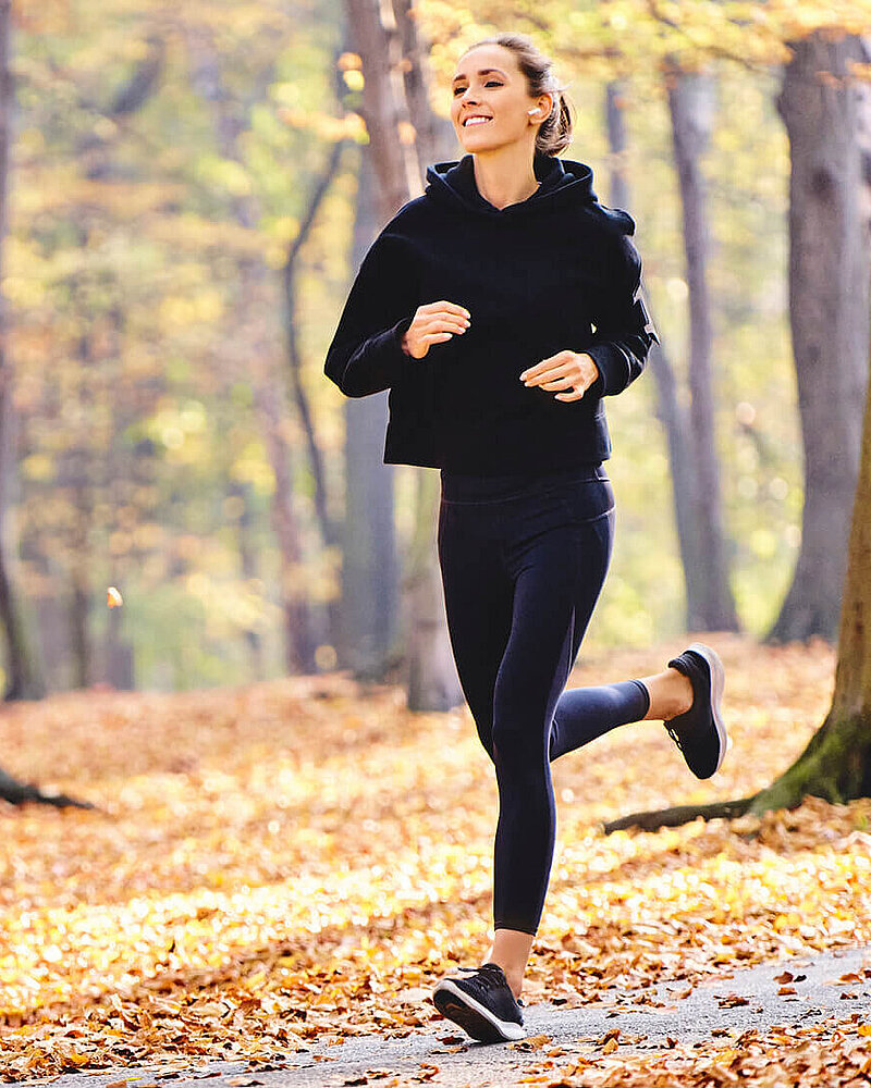 Eine Frau joggt durch einen Wald